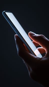 A hand holding a cell phone on blank white screen with a black background..