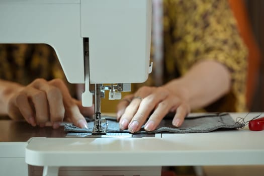Close up of fashion designer or tailor hands sewing fabric on a sewing machine.