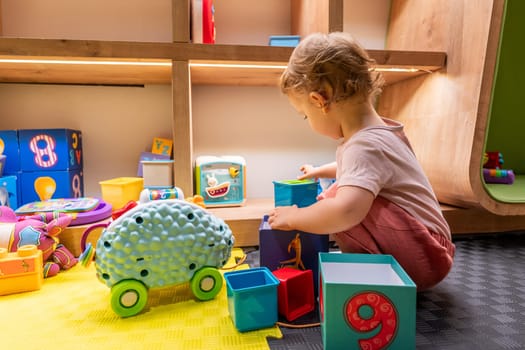 Young toddler playing with colorful blocks and engaging toys in a learning space