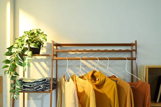 Stylish fashion designer studio with clothing rack with warm toned garments.