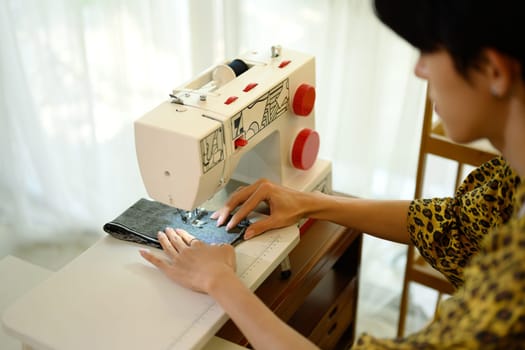 Close up of fashion designer or tailor hands sewing fabric on a sewing machine.