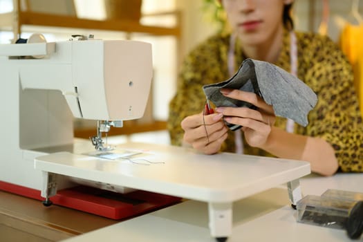 Close up of fashion designer or tailor hands sewing fabric on a sewing machine.