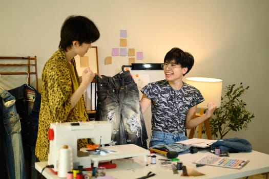 Fashion entrepreneurs celebrating their latest clothing design in studio.
