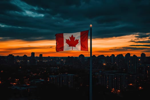 A huge Canadian flag flutters in the sky over a large city at sunset.