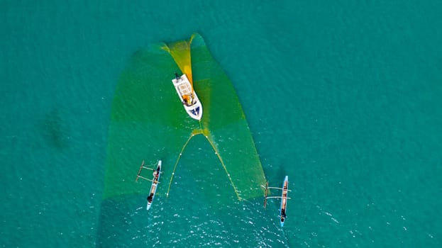 Sri Lanka - August 25, 2021: Aerial view of fishermen on a fishing boat is casting a net for catching fish. Sri Lanka.