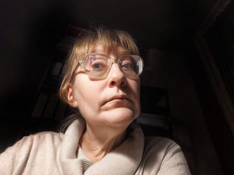 Blonde middle-aged woman poses for a selfie in her cozy indoor space, capturing a moment of fun and lightheartedness.