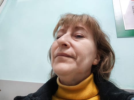 A cheerful blogger in her 50s enjoys a moment of fun as she takes a selfie, radiating confidence and joy.
