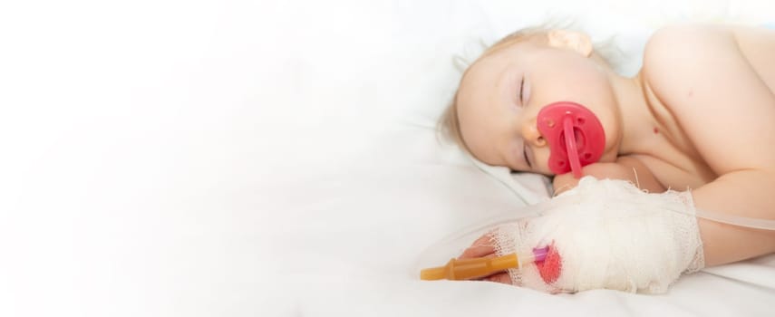 Babygirl sick and sleeping on patient bed at the hospital. Saline intravenous or (IV)drip in baby patient hand. Poor baby looks tired and exhausted.IV fluid replacement or correcting the dehydration. High quality photo