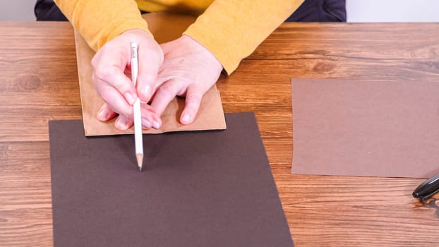 Step by step. Teacher guides online class through making a paper puppet from a brown bag, creatively using a wooden surface as a workspace.