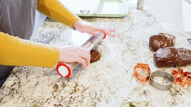 Using an adjustable rolling pin to roll out gingerbread cookie dough on the elegant marble counter in a modern kitchen, getting ready for festive holiday baking.
