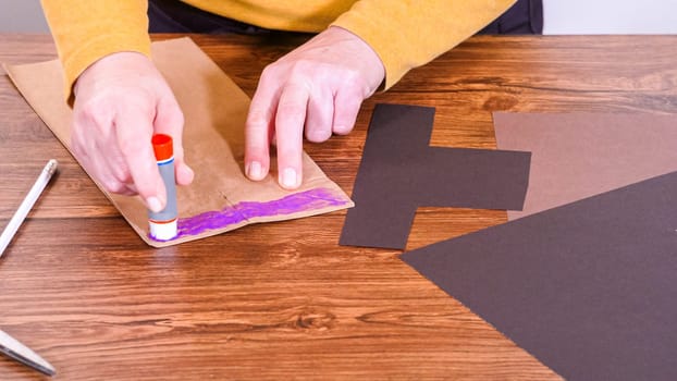 Step by step. Teacher guides online class through making a paper puppet from a brown bag, creatively using a wooden surface as a workspace.