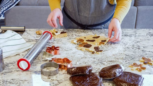 Using various festive cookie cutters, we're cutting out charming gingerbread cookies from the rolled dough on the sleek marble counter, bringing holiday cheer to the modern kitchen.