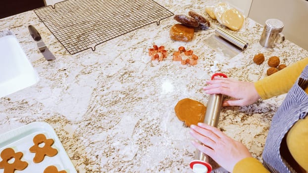 Using an adjustable rolling pin to roll out gingerbread cookie dough on the elegant marble counter in a modern kitchen, getting ready for festive holiday baking.