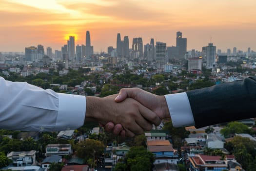 Two men shaking hands in front of a city skyline. Scene is professional and formal