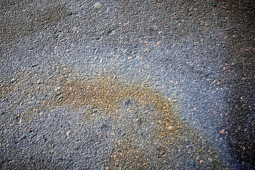 Perspective of bright petrol stains, displaying a textured ground with a range of colors on the street