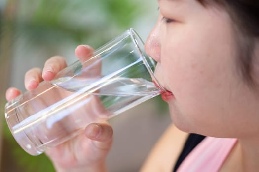 An overweight woman enjoying a refreshing glass of water, highlighting the importance of hydration in her weight loss and healthy lifestyle.