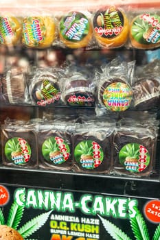 AMSTERDAM, THE NETHERLANDS - APRIL 15, 2019: Shop showcase window with cookies, cakes of cannabis as a souvenir in the store