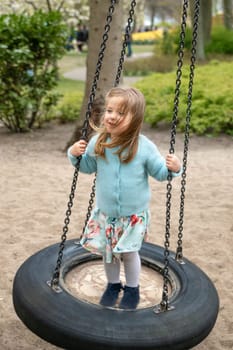 Girl of 4 years old riding on a swing in a park