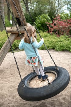 Girl of 4 years old riding on a swing in a park