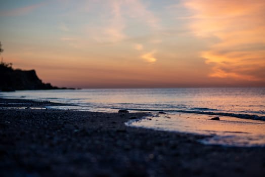 Beautiful seascape with bright horizon. The sun over the sea has painted the sky red. In the foreground is a beach and the surf washes the seashore.