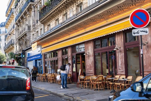 Paris with beautiful buildings, cars and people passing by on the street. Paris, France - February 10, 2025
