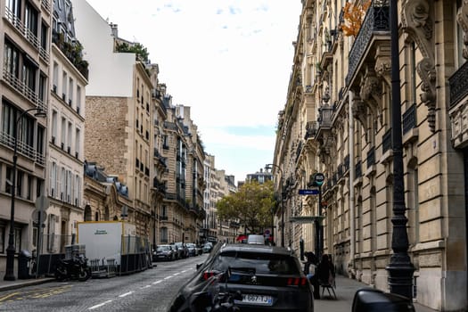 Paris with beautiful buildings, cars and people passing by on the street. Paris, France - February 10, 2025