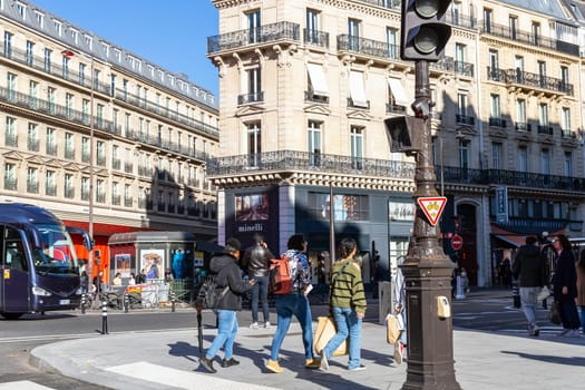 Paris with beautiful buildings, cars and people passing by on the street. Paris, France - February 10, 2025