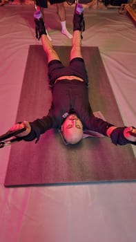 Determined athlete exercising with suspension straps under supervision of personal trainer in gym
