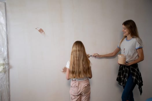 This captures a joyful moment shared between a mother and her daughter as they paint a wall in their home together
