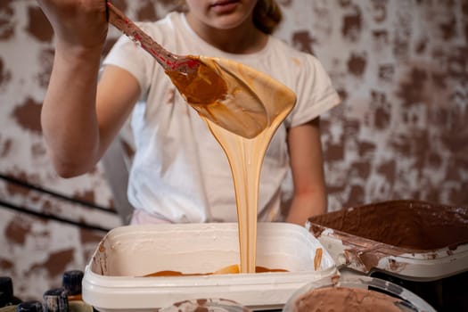 A young artist delightfully enjoys mixing a variety of colorful paint in a vibrant and creative studio environment