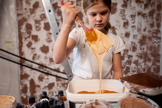A young girl is joyfully exploring her imagination while mixing colorful paint in a creative artistic setting
