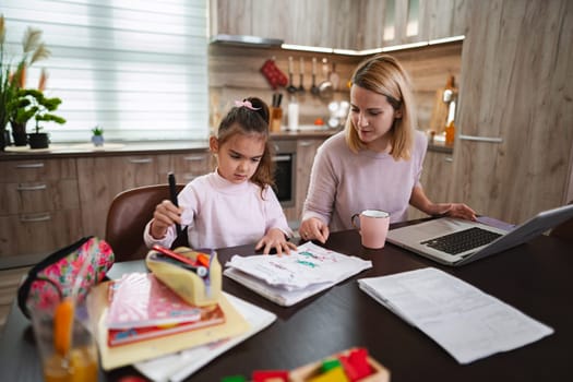A mother helps her daughter with art projects while enjoying quiet family time.