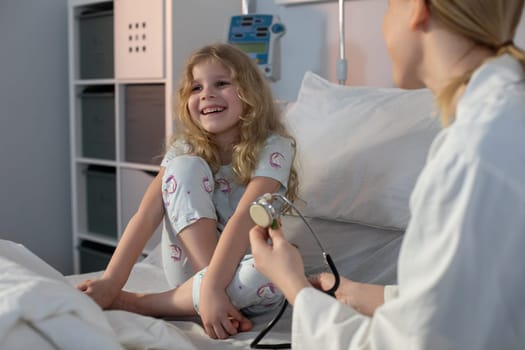 A young girl beams with joy while engaging in a cheerful interaction with a friendly nurse in a hospital room