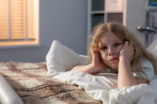 A young child lies peacefully in bed, looking contemplative and deep in thought in a softly lit room at night