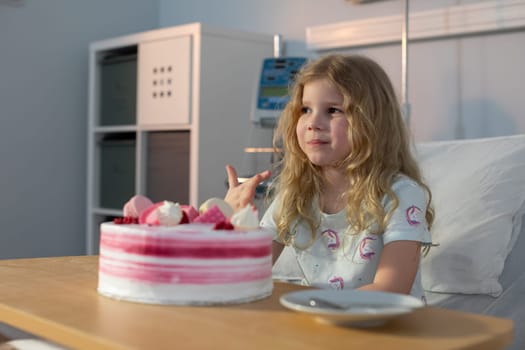 A young girl enjoys a colorful, decorated cake in the hospital, savoring a moment of joy and comfort