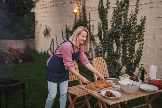 Cook prepares a delicious spread outdoors amidst lush greenery and warm lights.