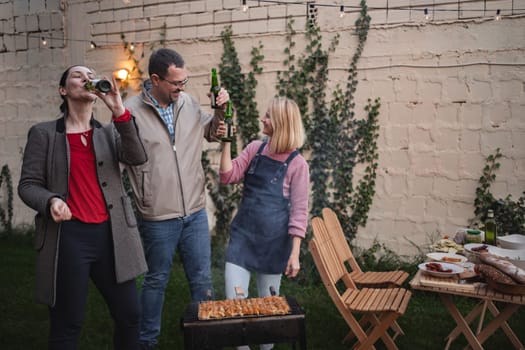 Three friends enjoy a lively barbecue together on a warm evening.