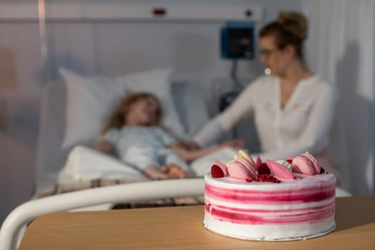 A tender moment shared between a loving mother and her child in a hospital room with a delightful cake