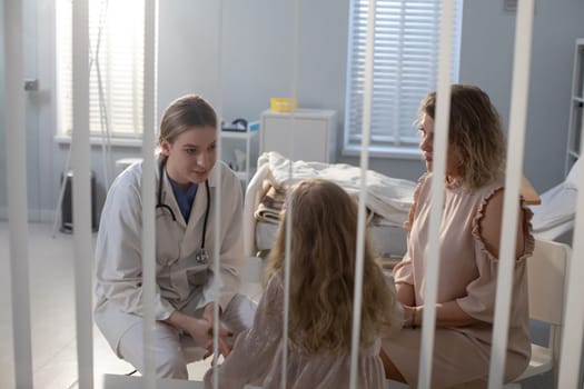 A caring medical professional interacts attentively with a young patient and her mother in a hospital