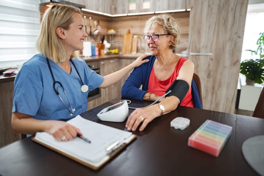 Nurse warmly engages with elderly patient while monitoring health.