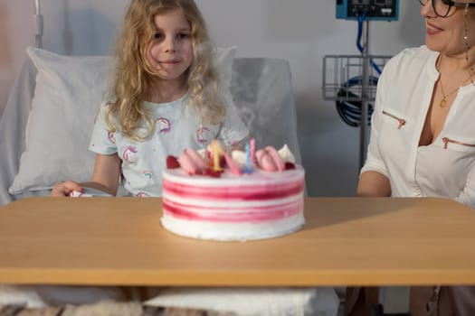 In a hospital setting, a young girl and an adult joyfully celebrate a special occasion together with a cake