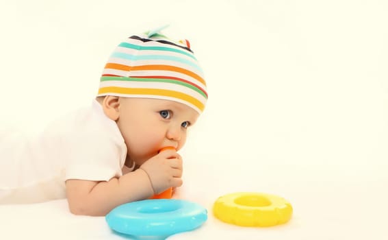 Happy little baby playing with toys while sitting on floor on white studio background