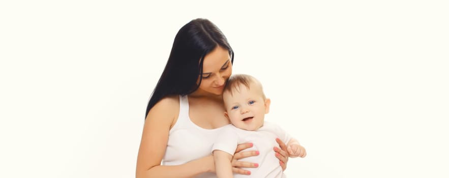 Happy smiling young mother playing with cute baby sitting together on the floor on white studio background