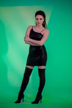 A stylish woman poses in a stunning black dress and overtheknee boots, showcasing modern fashion brilliantly