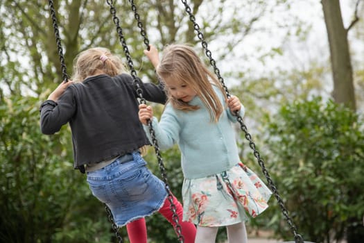 The girls are riding on a swing in a park