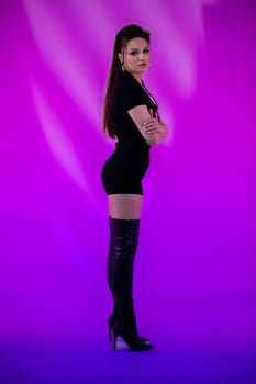 A confident woman in a sleek black mini dress and striking thighhigh boots on a vibrant purple background