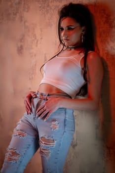 A young woman poses confidently in stylish ripped jeans and a trendy crop top, showcasing urban fashion