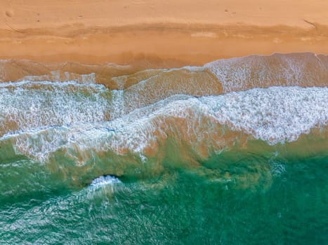 Golden sand beach on Kauai Island, Hawaii, meets turquoise ocean waves. Aerial perspective highlights the vibrant, untouched coastline and serene setting.