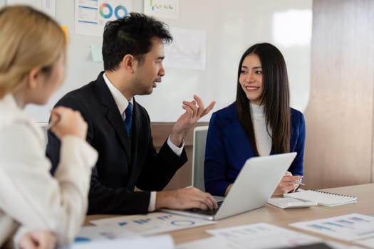 A female and male professional present financial strategies on charts, fostering teamwork in a contemporary office setting.