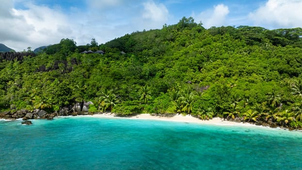 Coastline surrounded by lush vegetation and white sandy beach. Seychelles, Mahe. Butzel Beach.
